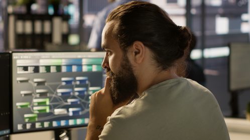 Homem digita no computador e observa tela com pipeline de dados À sua frente