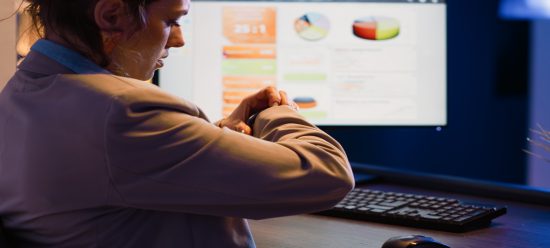 mulher olhando para relógio enquanto busca dados com a falta de ferramentas de bi