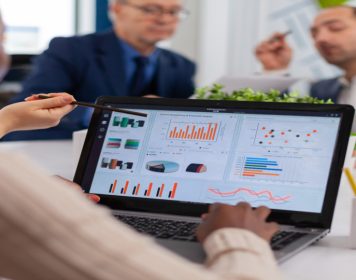 time sentado ao redor de uma mesa de reuniões com notebook sobre a superfície demonstradno planilhas e gráficos de dados