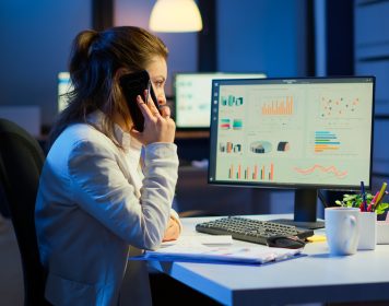 mulher gerente olha para computador com gráficos de dados sinalizando a importânica de uma ingestão de dados que é feita corretamente