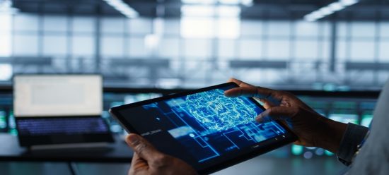 tablet segurando por mãos humanas com tela mostrando elemrntos relaiconados à automação inteligente em cores azuis