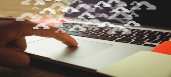mãos humanas digitando em teclado de noteboo cinza com símbolos de nuvem branco com sinais de seta dentro deles, simbolizando o replatforming