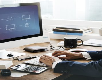 homem vestindo terno digita em computador que na tela mostra estratégia de gerenciamento de nuvem, simbolizando o lift-and-shift ou rehost.