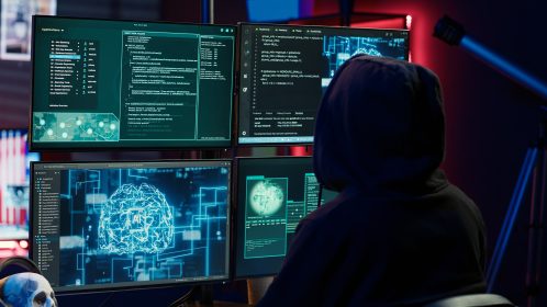 homem vestindo capuz preto mexendo em computadores, o que representa os ataques protegidos pelo hardening